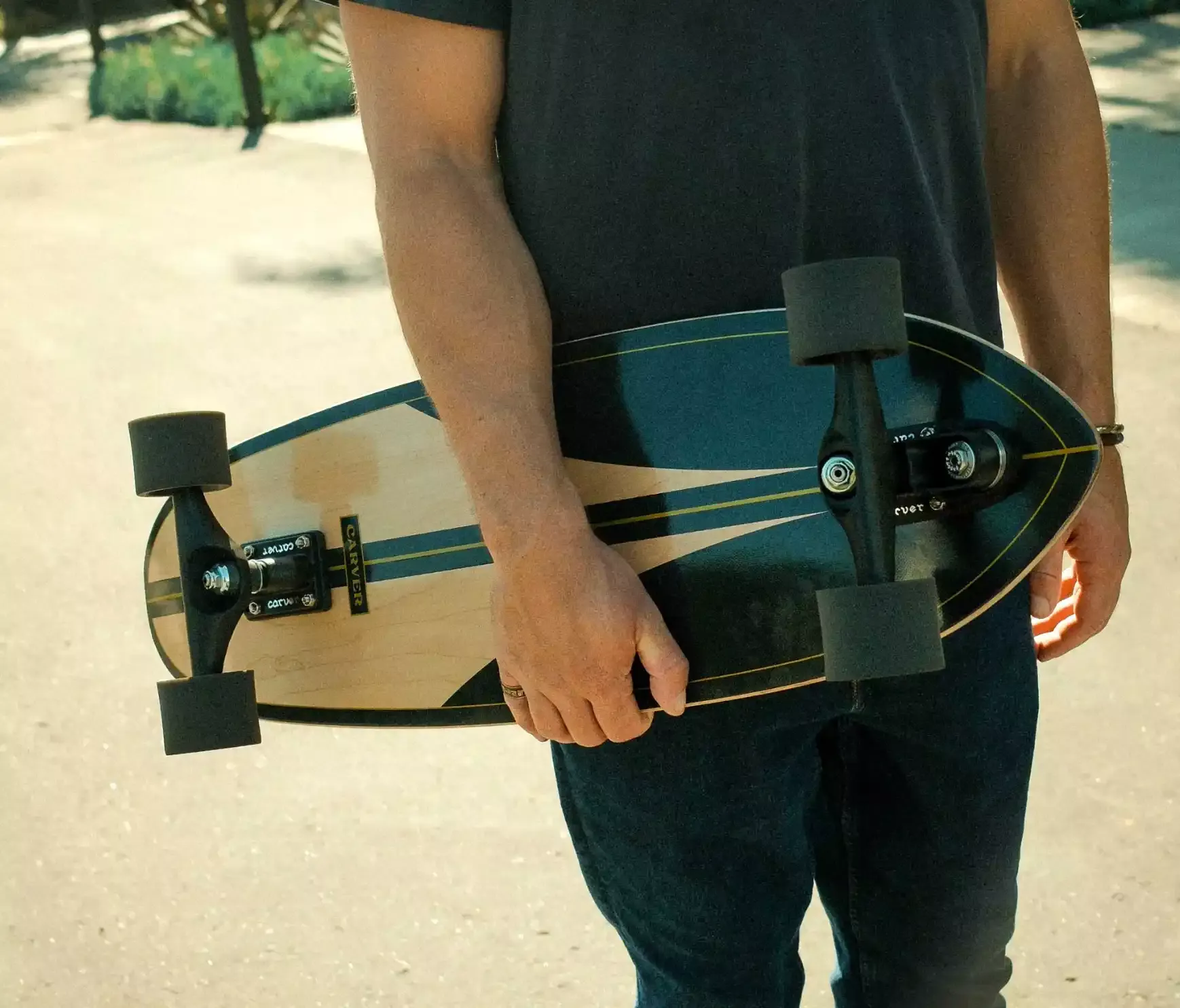 Persona che tiene una longboard eletto con ruote grandi, in stile skater, all’aperto sotto sole.