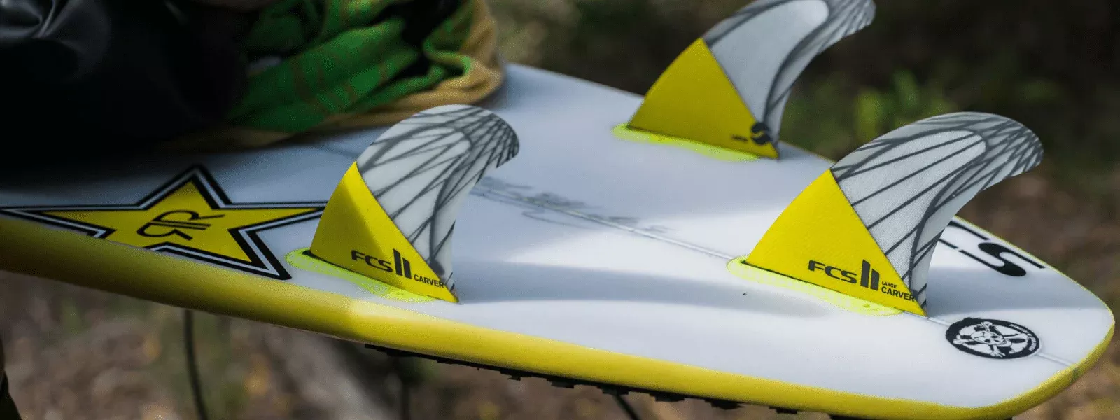 Tablas de surf con aletas de seguridad amarillas instaladas, sobre una pala blanca con borde amarillo y logotipos.